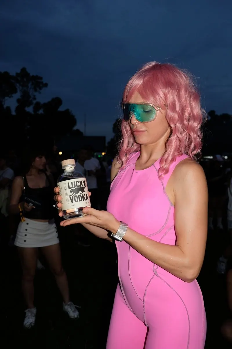 A girl in pink holding a bottle of Lucky Vodka