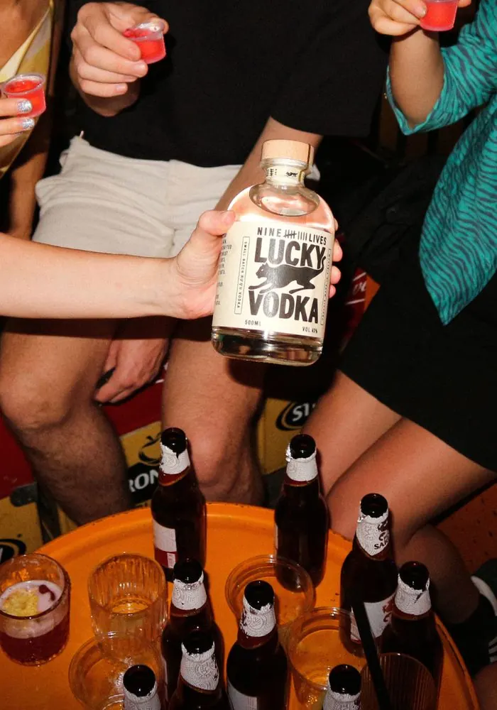 Friends doing shots around a bottle of Lucky Vodka