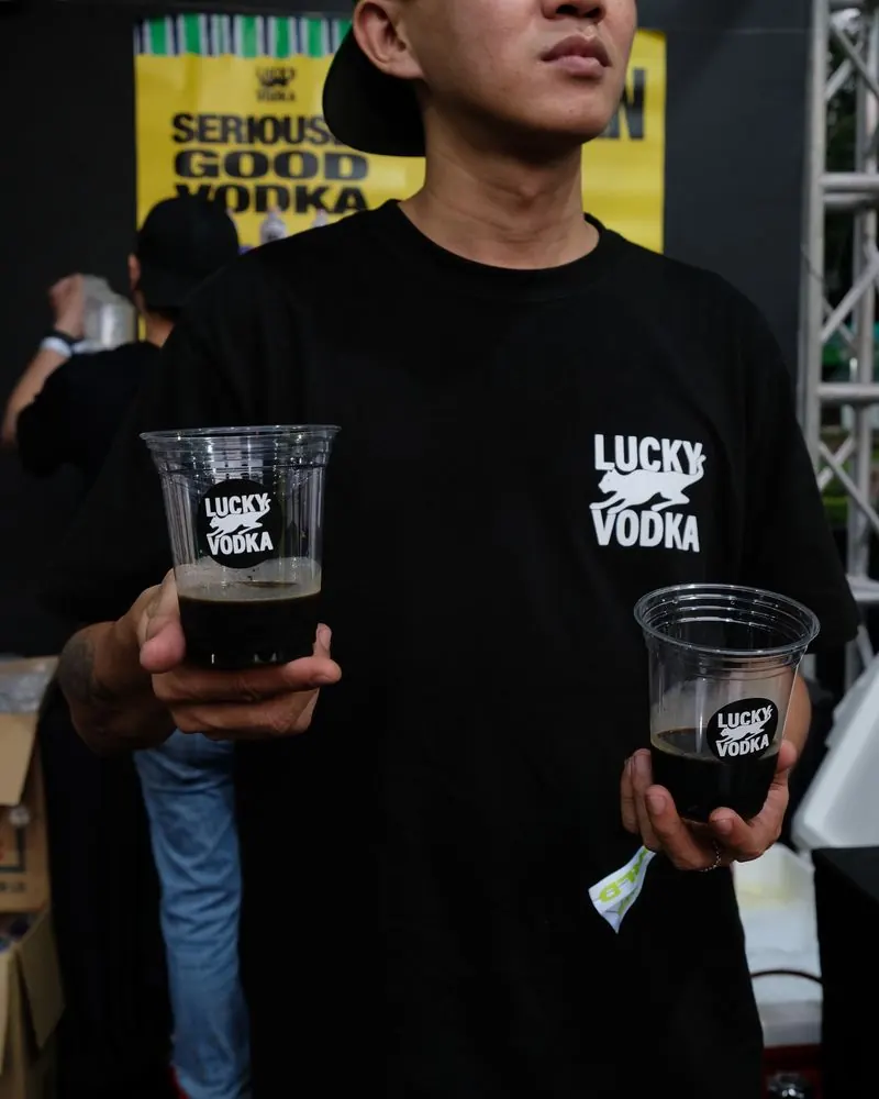 A guest holding two iced Lucky Vodka drinks